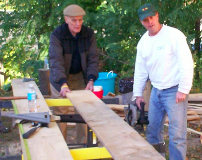 Andy Clark (right) with his dad Jim Clark working on one of the 1x12” rough-cut hemlock boards used to restore the original “board and batten” siding for the barn.  